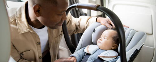 Kindersitz-Norm & Zulassungsvorschriften Kind in Babyschale mit Vater im Auto