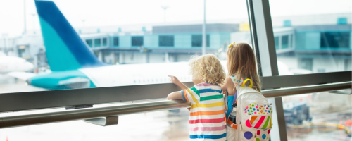 Zwei Kinder schauen im Flughafen aus dem Fenster auf ein Flugzeug Zwei Kinder schauen im Flughafen aus dem Fenster auf ein Flugzeug