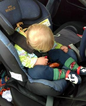 Kind im Kindersitz mit nach vorne gefallenem Kopf Kind im Kindersitz mit nach vorne gefallenem Kopf